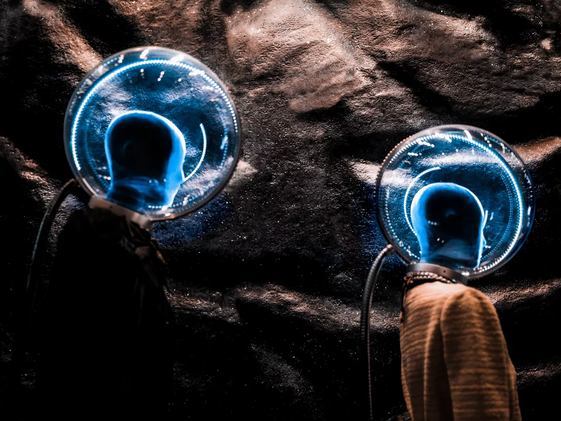 close-up-view-mannequins-wearing-illuminated-glass-spheres-against-rocky-surface